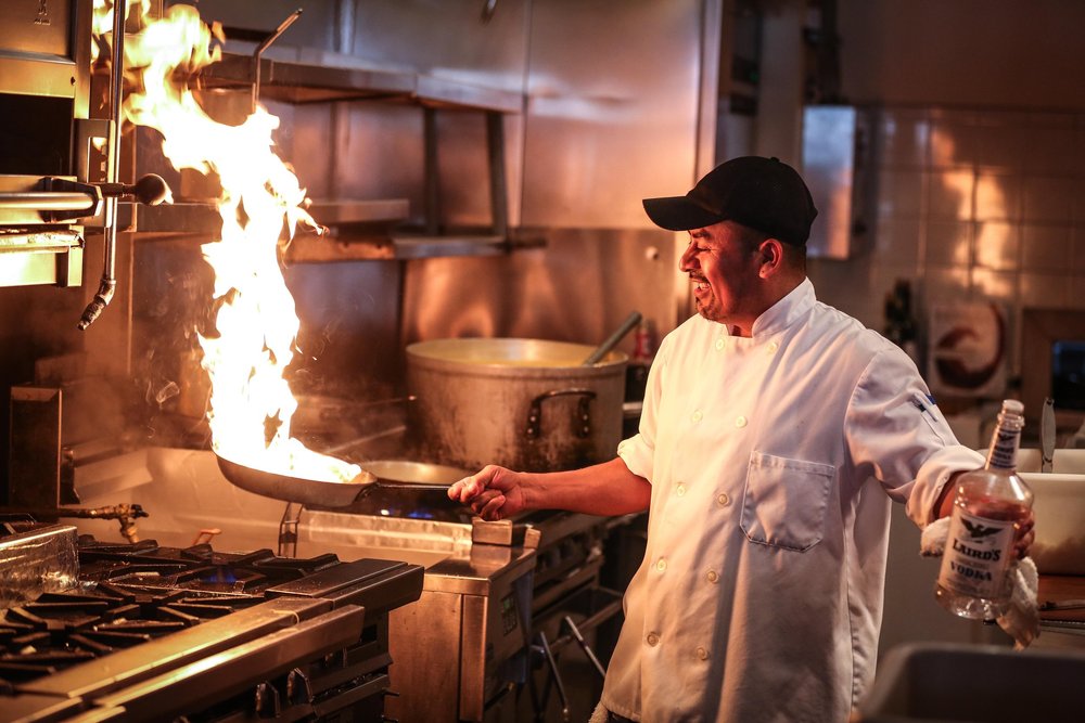 Cocinero trabajando frente a una estufa en una cocina profesional